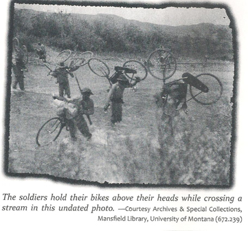 The soldiers hold bikes above their heads while crossing a stream